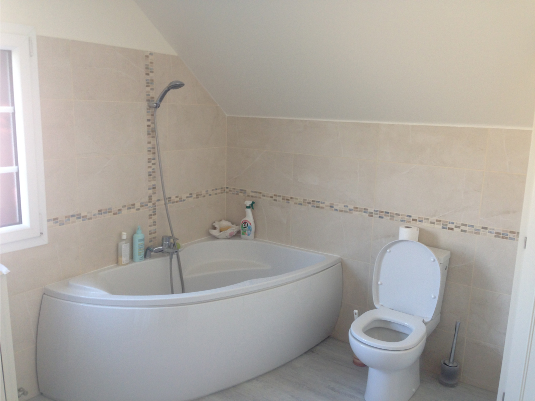 Salle de bain classique avec carrelage blanc, wc classique et baignoire design.