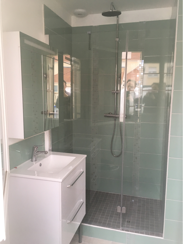 Salle de bain avec carrelage vert et pommeau en hauteur.
