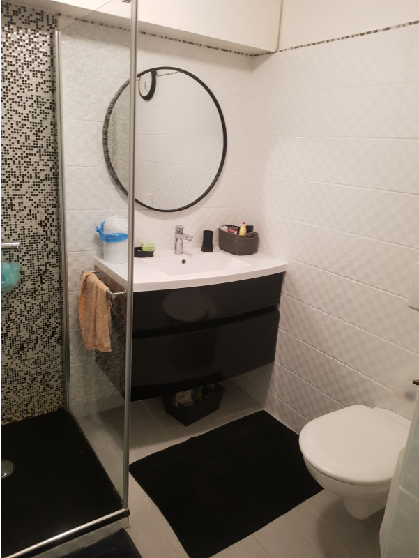 Salle de bain moderne avec wc suspendu et carrelage beige.